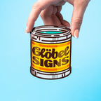 Hand holding a custom vinyl sticker canister labeled 'Göbel Signs' against a light blue background.