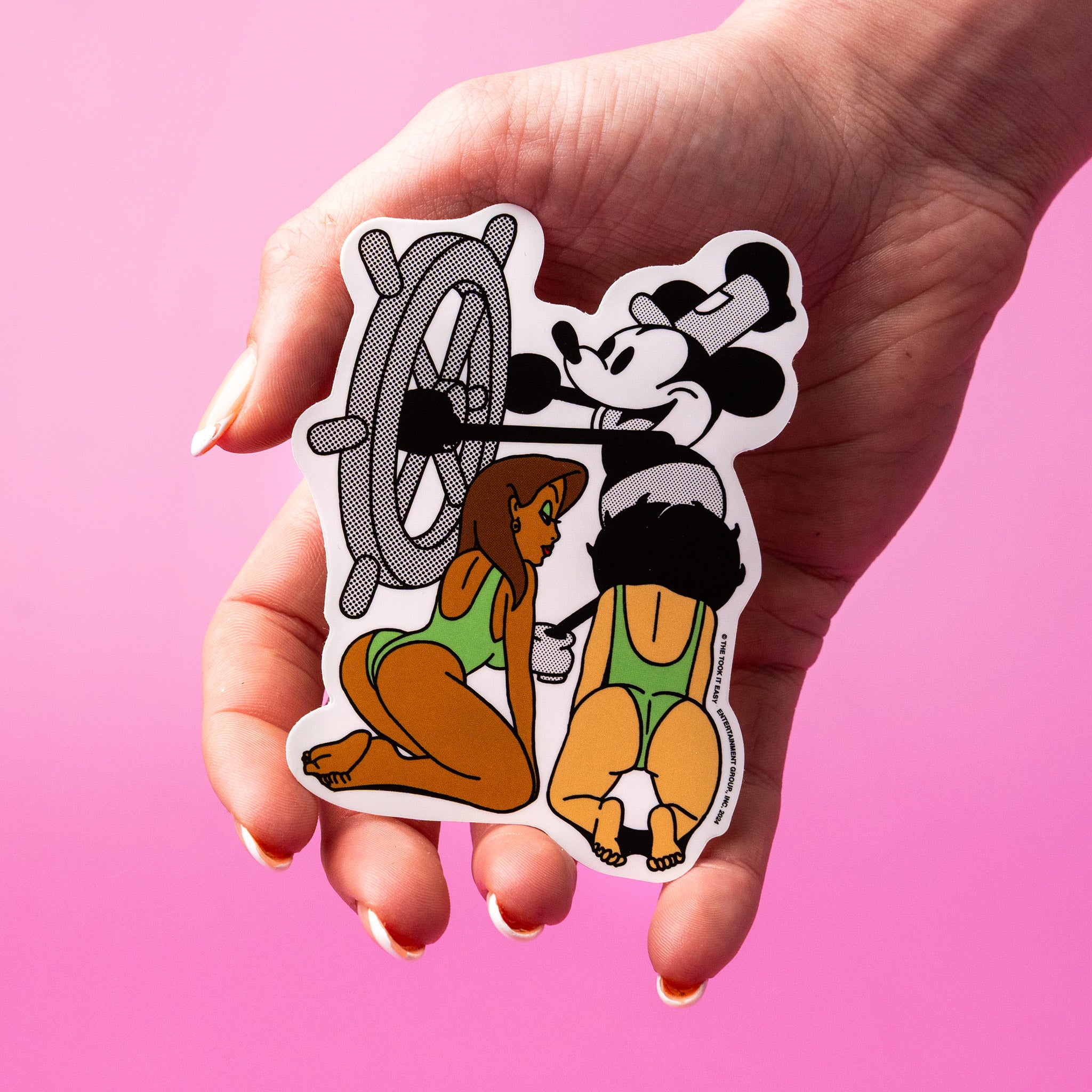 Hand holding a custom vinyl sticker with cartoon characters on a pink background.